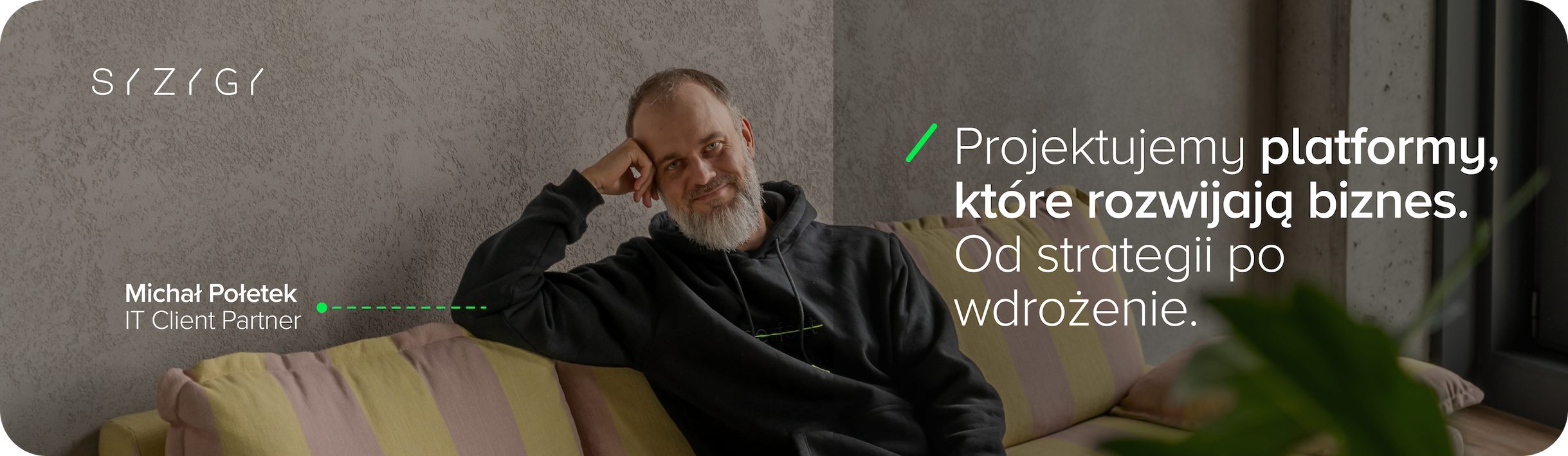 Michał Połetek, IT Client Partner w SYZYGY, na tle biura z banerem promującym projektowanie i wdrażanie platform cyfrowych dla biznesu.